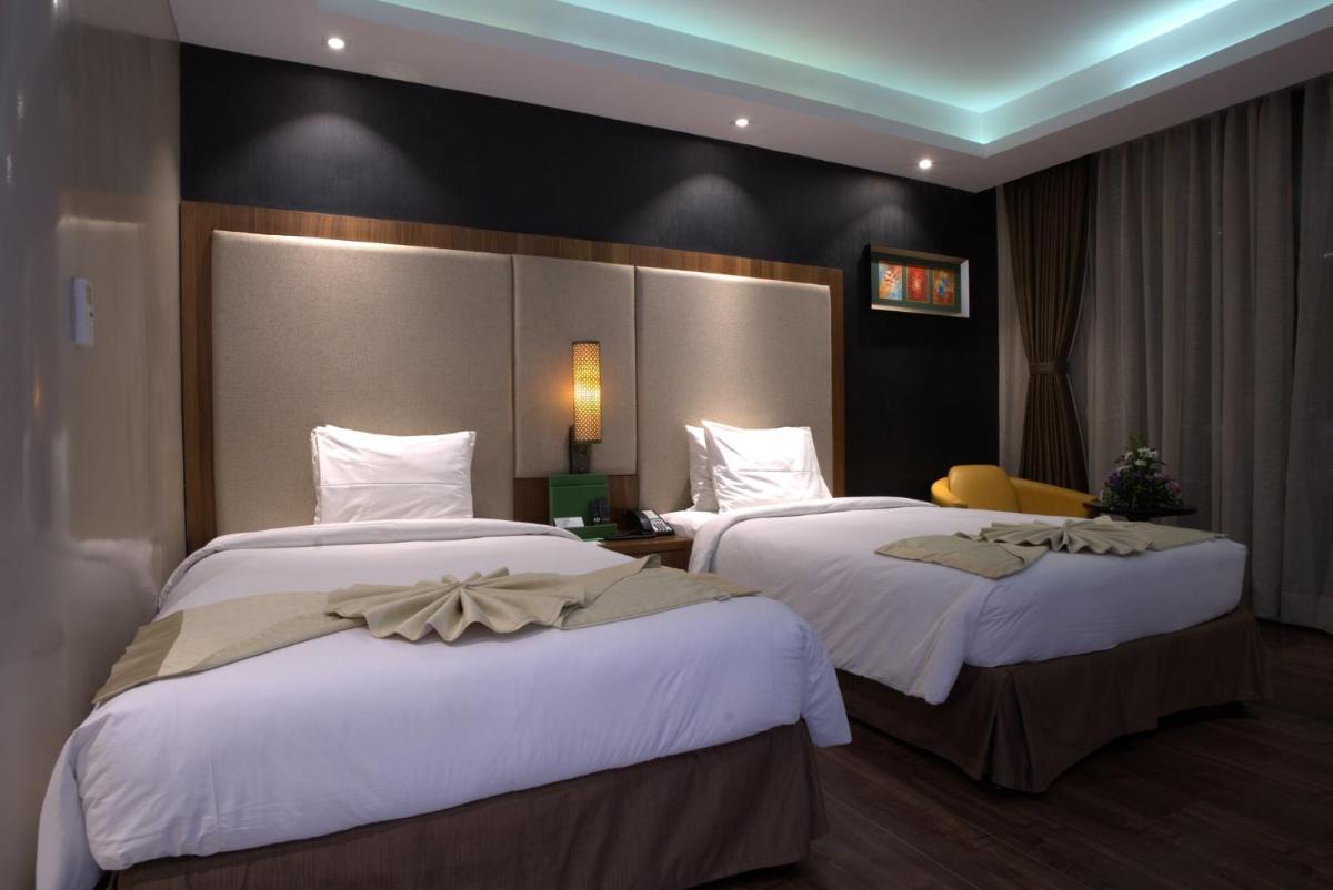 a hotel room with two beds with white sheets at Holiday Inn Kolkata Airport by IHG in Kolkata