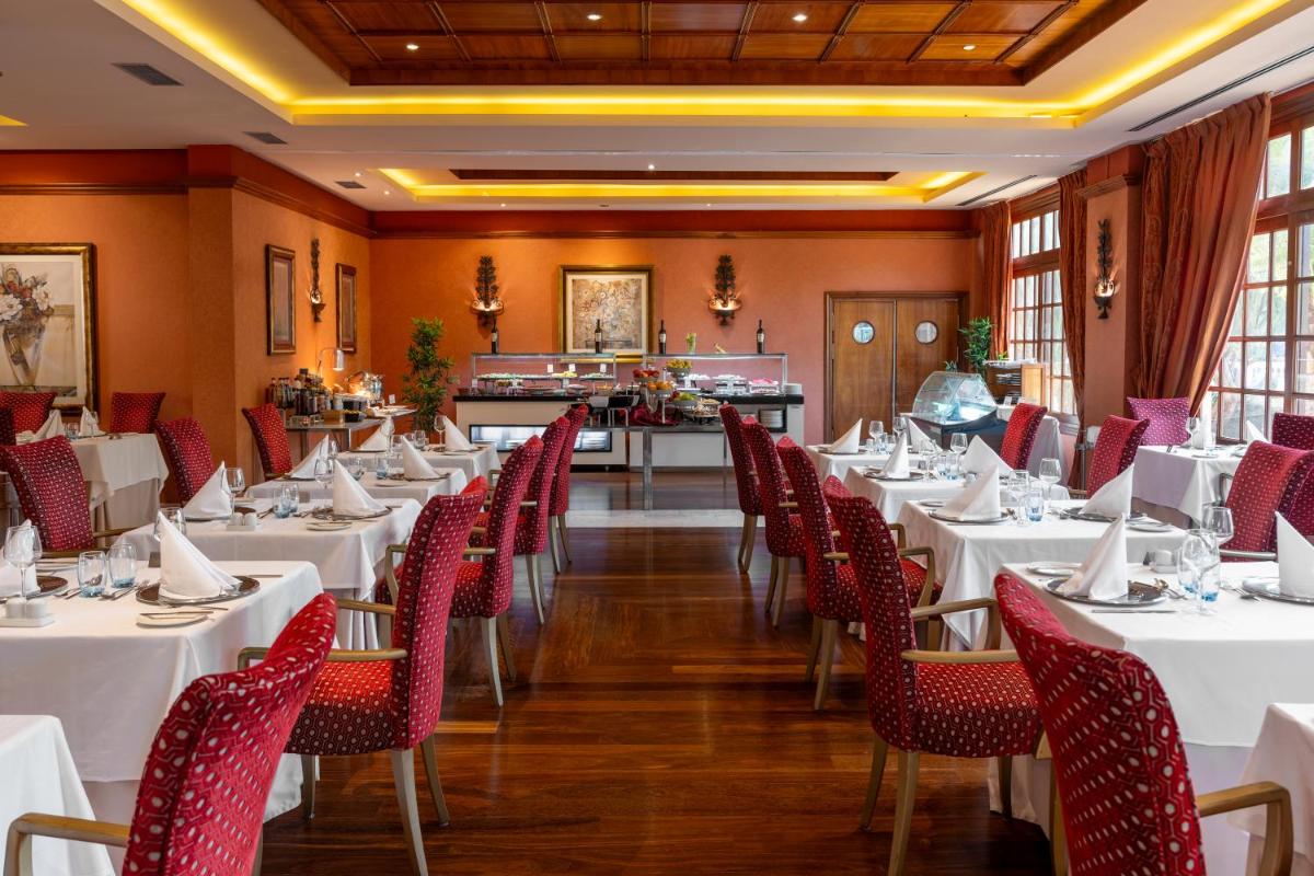 Un comedor con mesas blancas y sillas rojas. en Elba Palace Golf Boutique Hotel - Adults Only, en Caleta de Fuste