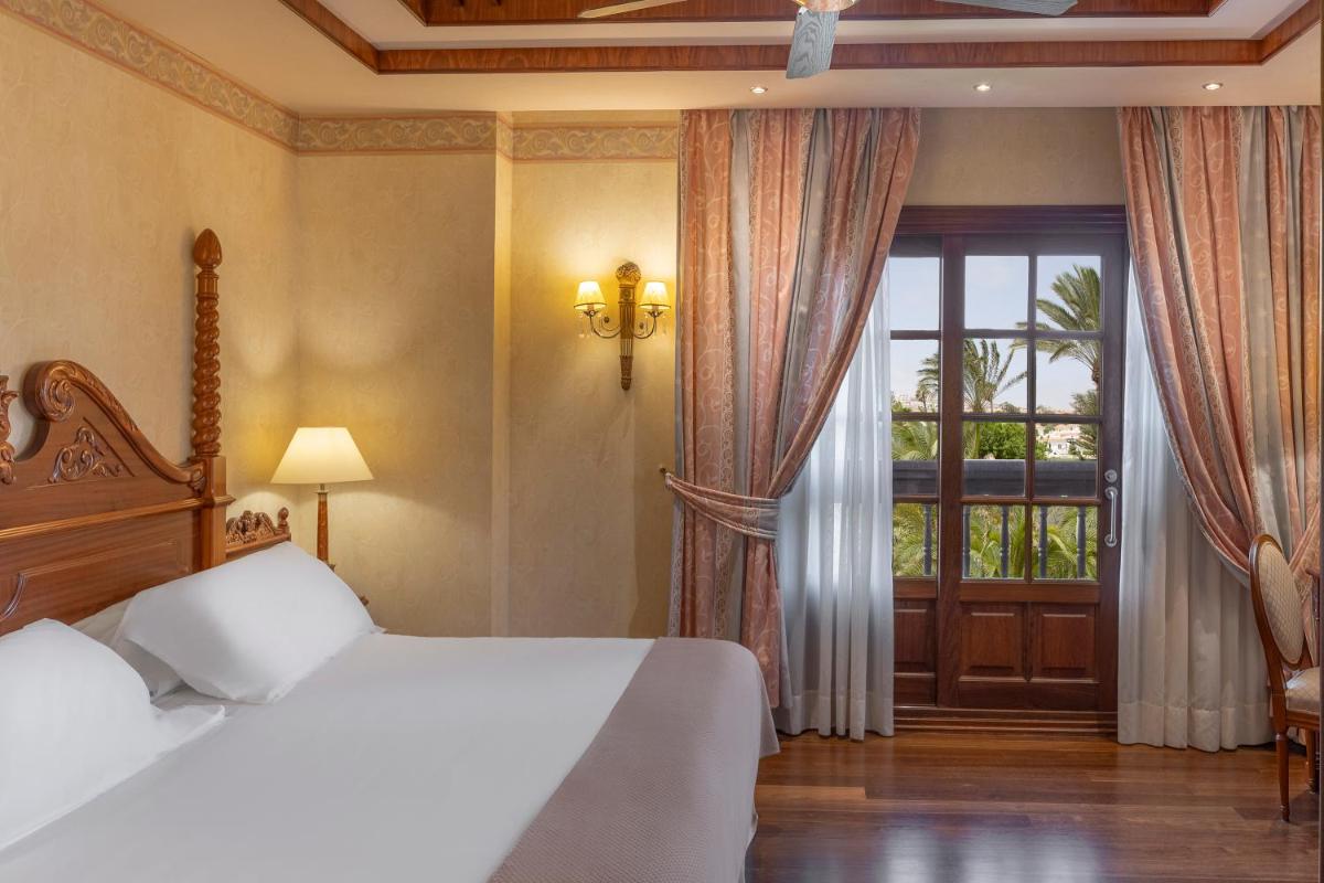 Un dormitorio con una cama y una ventana grande. en Elba Palace Golf Boutique Hotel - Adults Only, en Caleta de Fuste