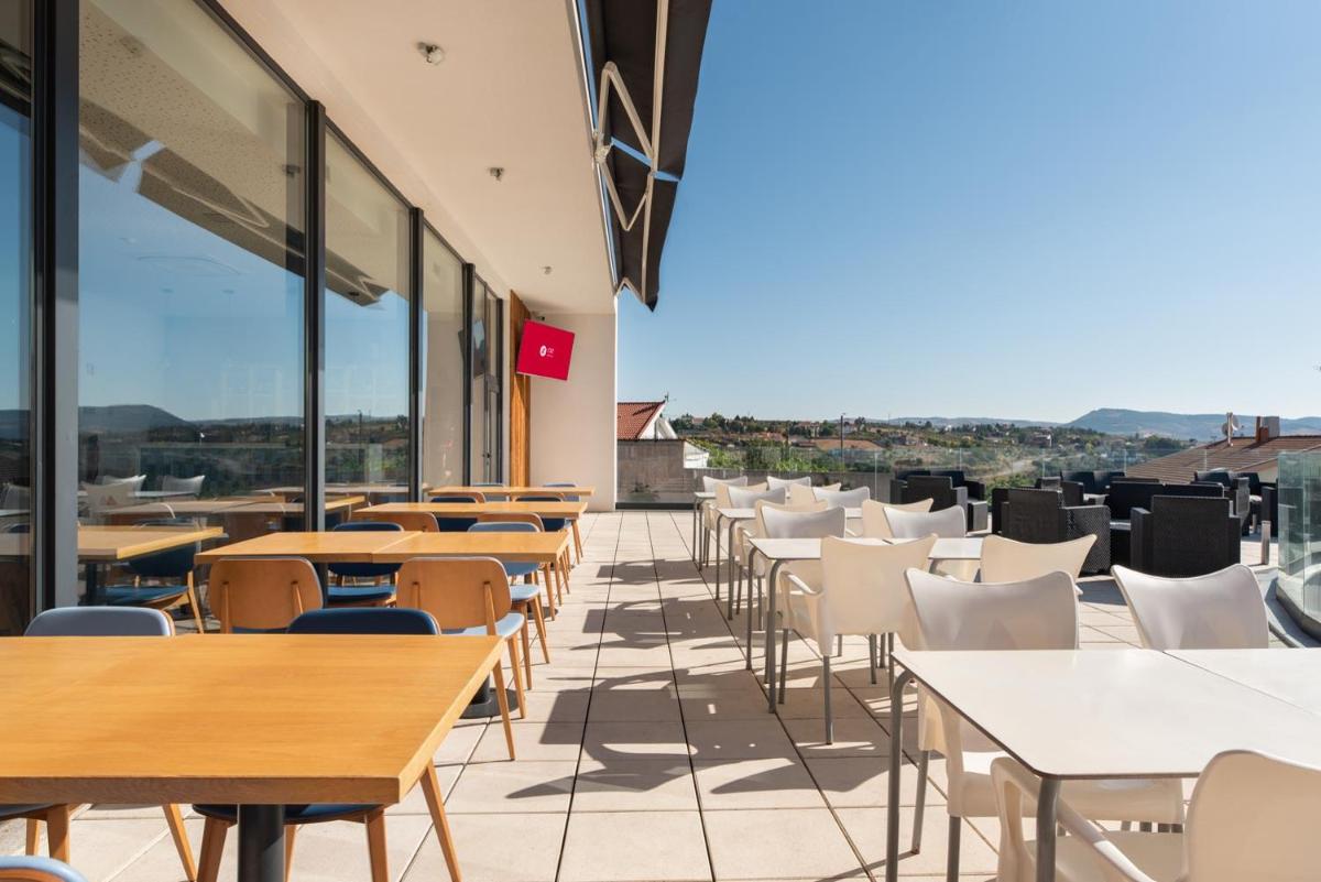 uma cafeteria com mesas e cadeiras no terraço em Exe São Lázaro em Brangança