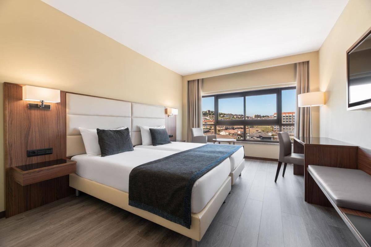 um quarto de hotel com uma cama, uma escrivaninha e uma janela em Exe São Lázaro em Brangança