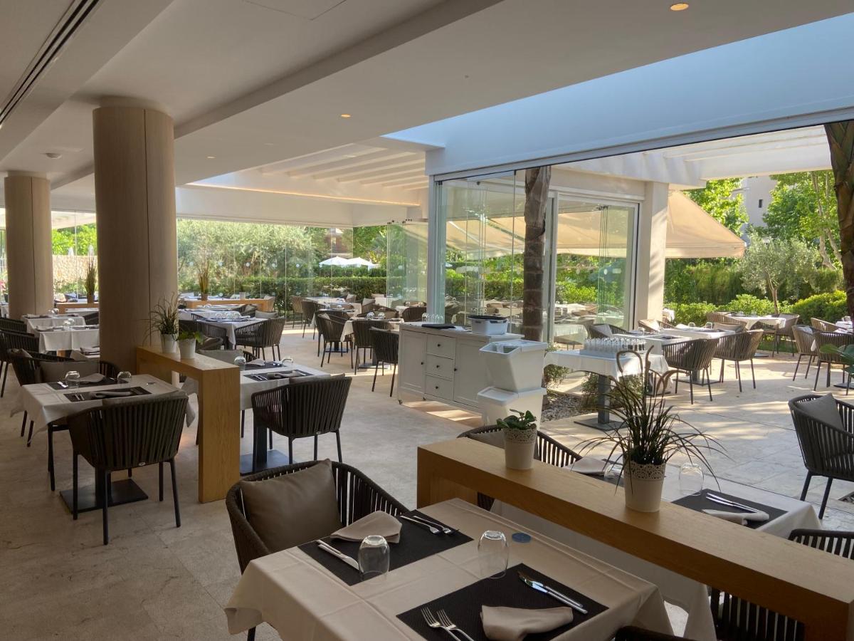 Un restaurante con mesas y sillas y un gran ventanal. en Canyamel Park Hotel & Spa - 4* Sup - Adults only (+16), en Canyamel