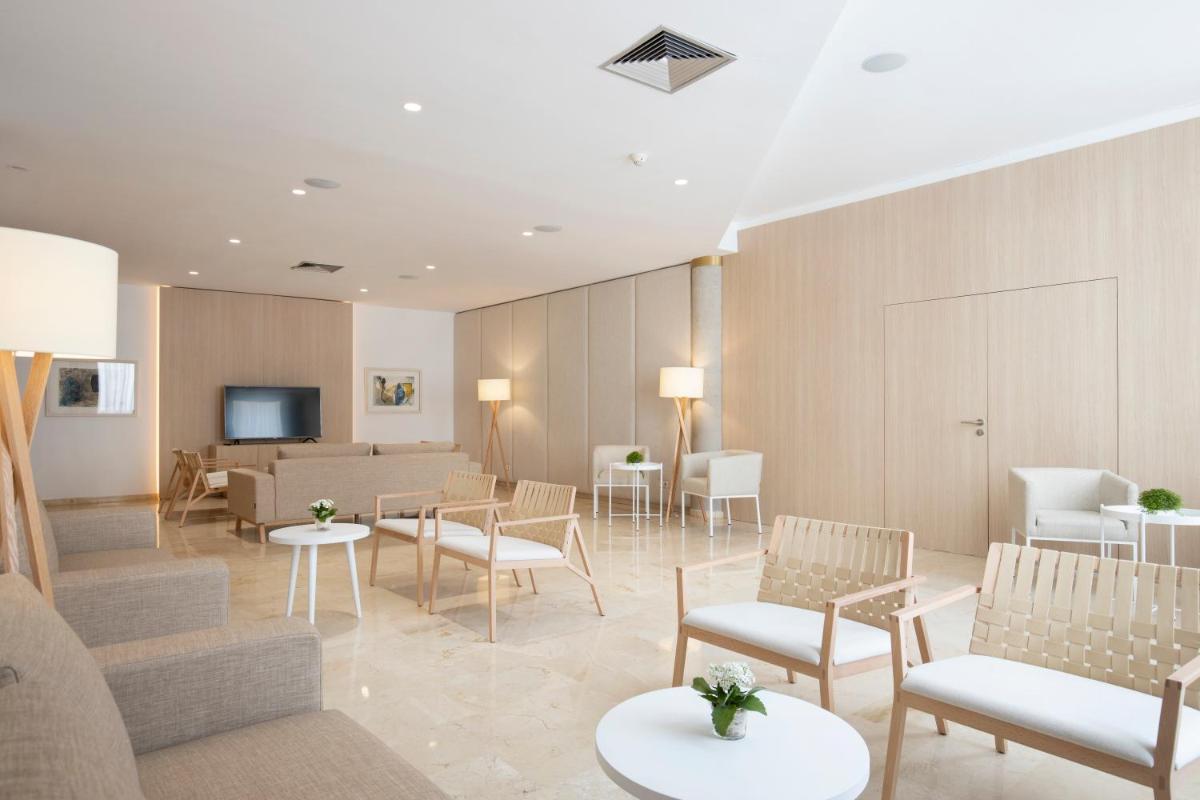 Una sala de espera con sillas y mesas y un televisor. en Canyamel Park Hotel & Spa - 4* Sup - Adults only (+16), en Canyamel