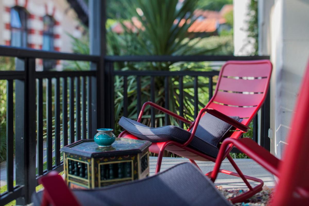 un groupe de chaises disposées sur une véranda avec une table dans l'établissement Hôtel Ville d'Hiver, à Arcachon