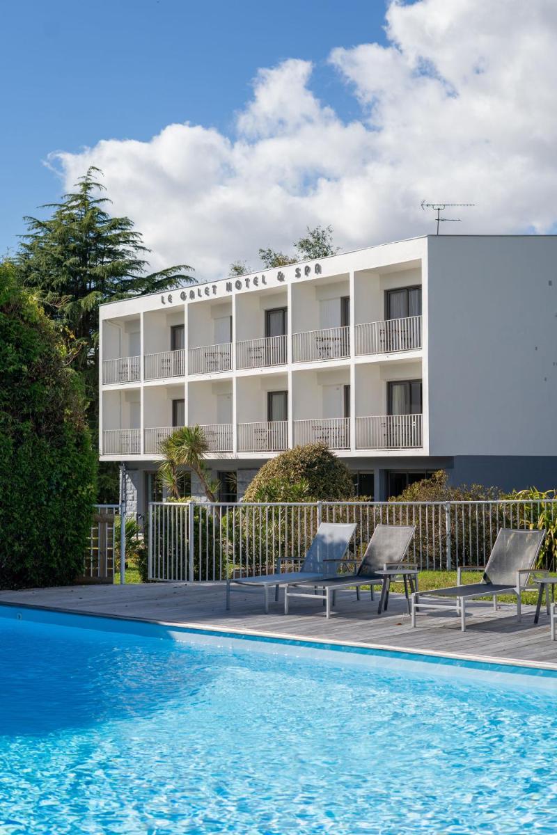 un hôtel avec une piscine devant un immeuble dans l'établissement Le Galet Hotel & Spa, à Saint-Philibert