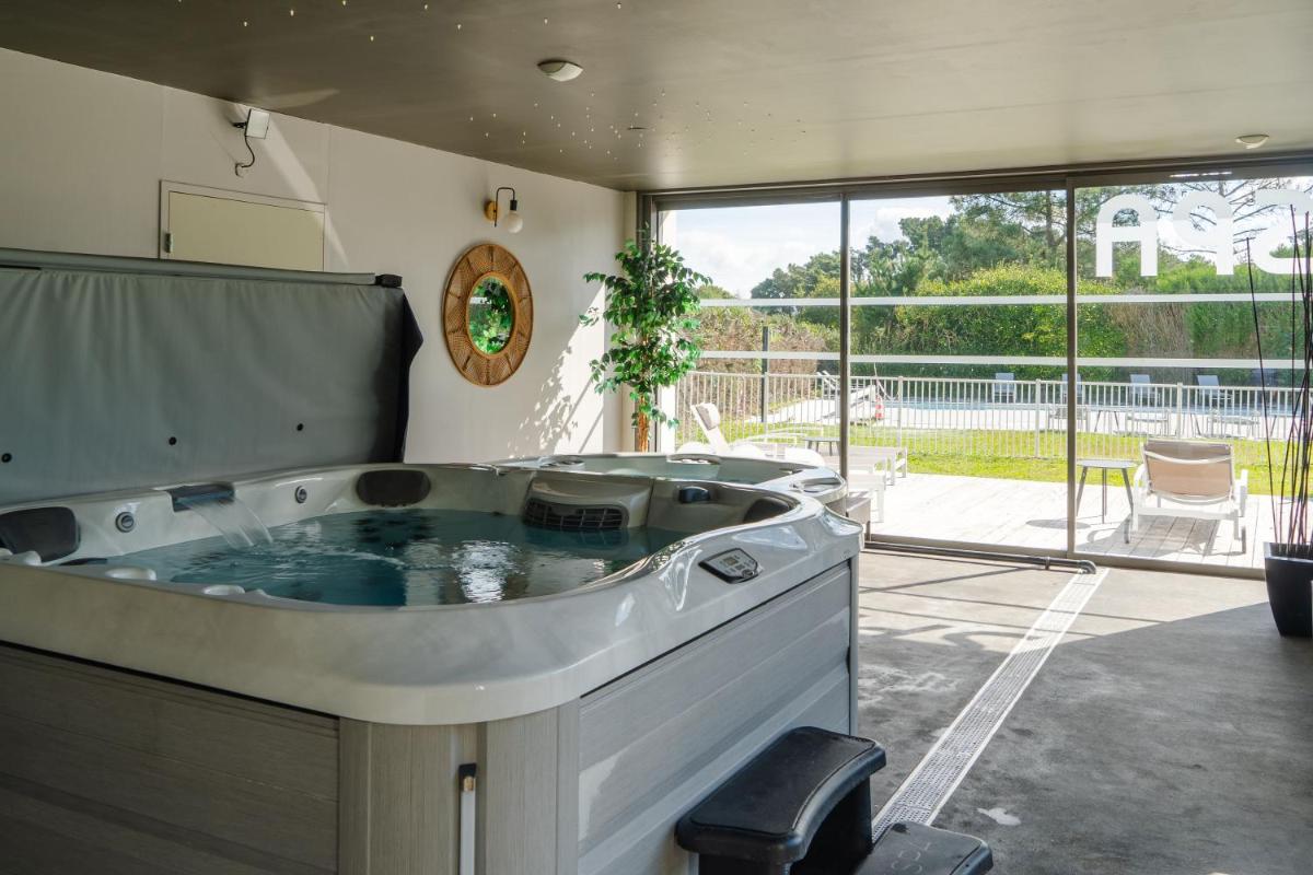 une grande baignoire dans une pièce avec une grande fenêtre dans l'établissement Le Galet Hotel & Spa, à Saint-Philibert