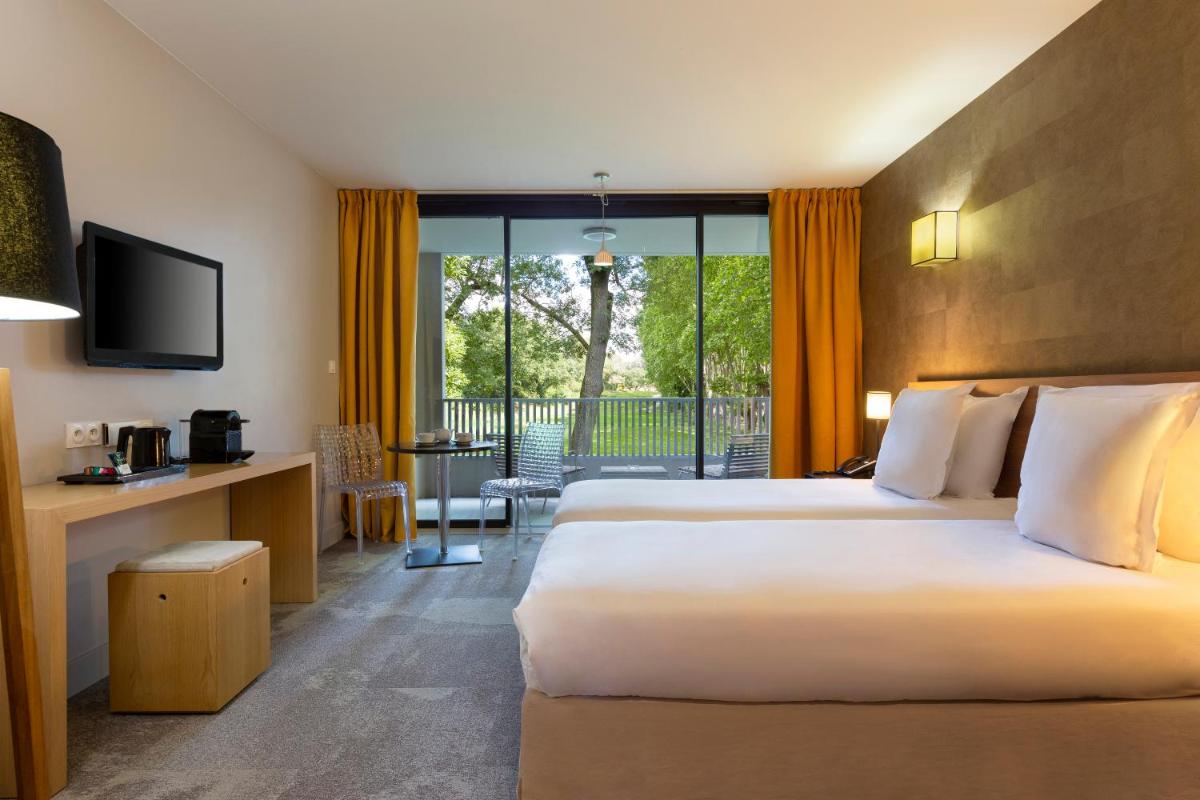 une chambre d'hôtel avec deux lits et un balcon dans l'établissement Hôtel du Golf, à Mallemort