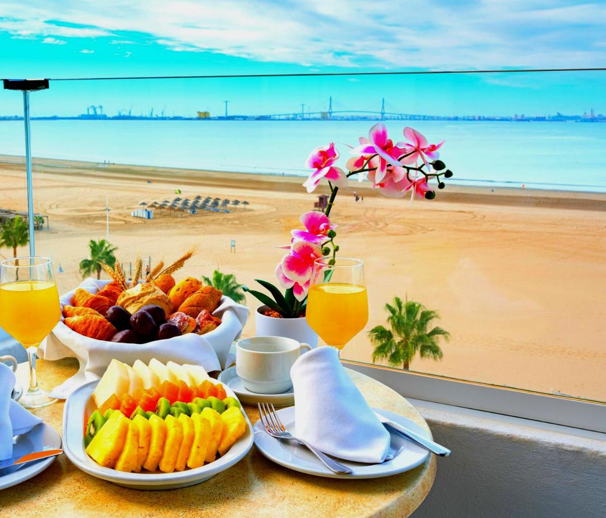 una mesa con platos de fruta y vistas a la playa en Hotel Puerto Bahía & Spa, en El Puerto de Santa María