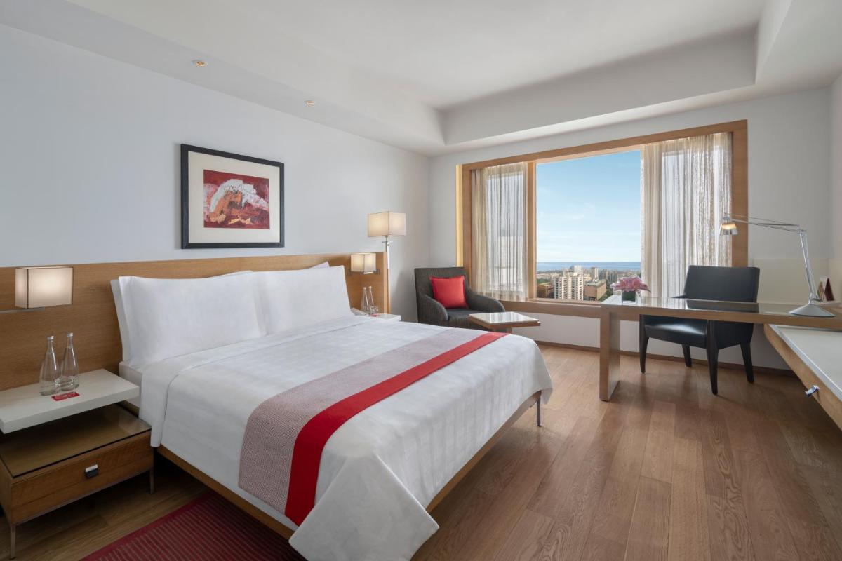 a hotel room with a bed and a desk and a window at Trident Nariman Point in Mumbai a hotel room with a bed and a desk and a window at Trident Nariman Point in Mumbai