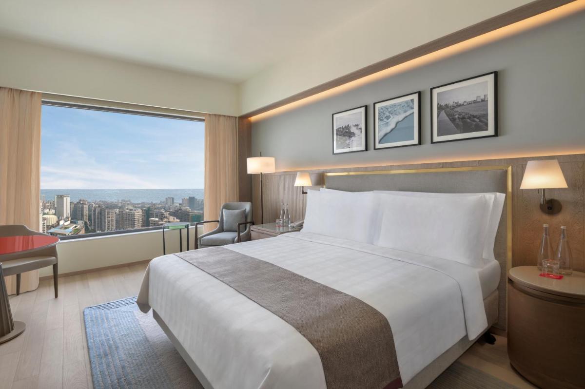 a hotel room with a bed and a large window at Trident Nariman Point in Mumbai a hotel room with a bed and a large window at Trident Nariman Point in Mumbai