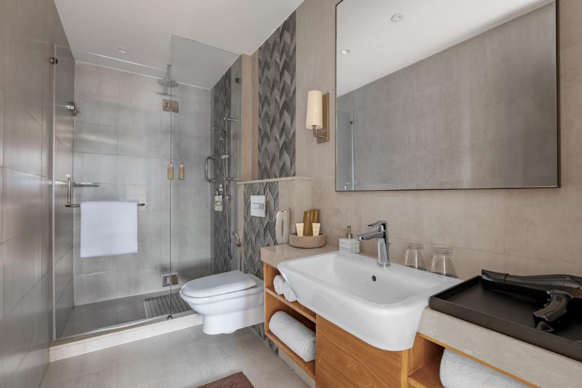 a bathroom with a sink and a toilet and a shower at The Astor - All Suites Hotel Candolim Goa in Candolim a bathroom with a sink and a toilet and a shower at The Astor - All Suites Hotel Candolim Goa in Candolim