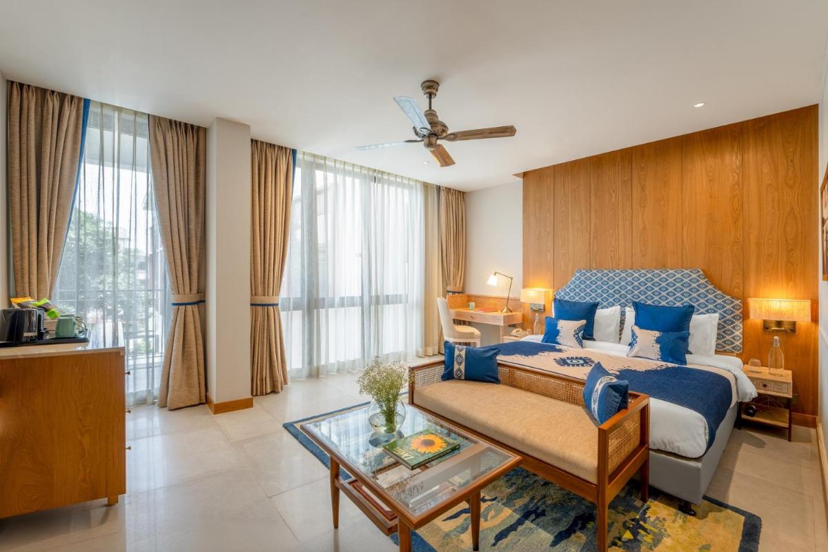 a bedroom with a blue bed and a table at The Astor - All Suites Hotel Candolim Goa in Candolim a bedroom with a blue bed and a table at The Astor - All Suites Hotel Candolim Goa in Candolim