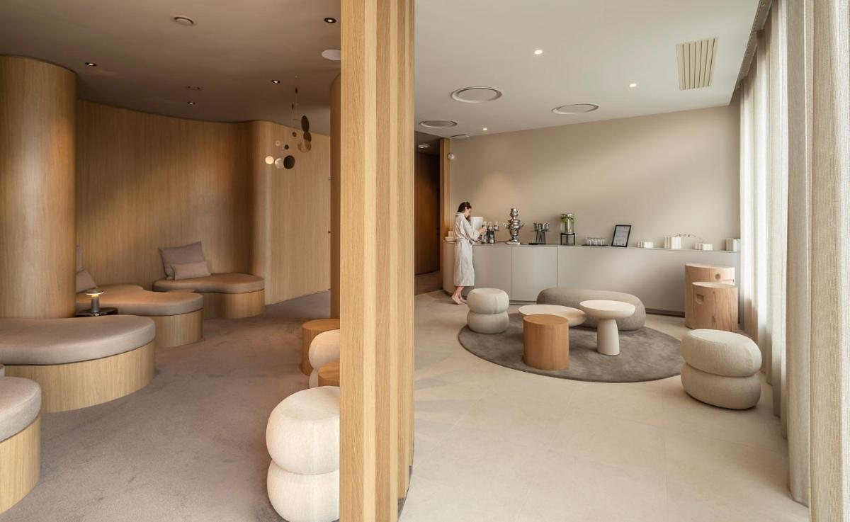 une femme debout dans une salle d'attente avec des tables et des chaises dans l'établissement Hôtel Horizon Resort Massane & Spa, à Baillargues