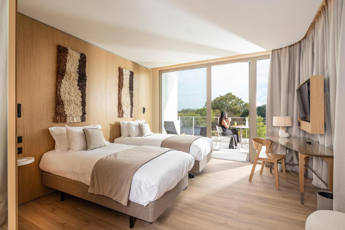 une chambre d'hôtel avec deux lits et un balcon dans l'établissement Hôtel Horizon Resort Massane & Spa, à Baillargues