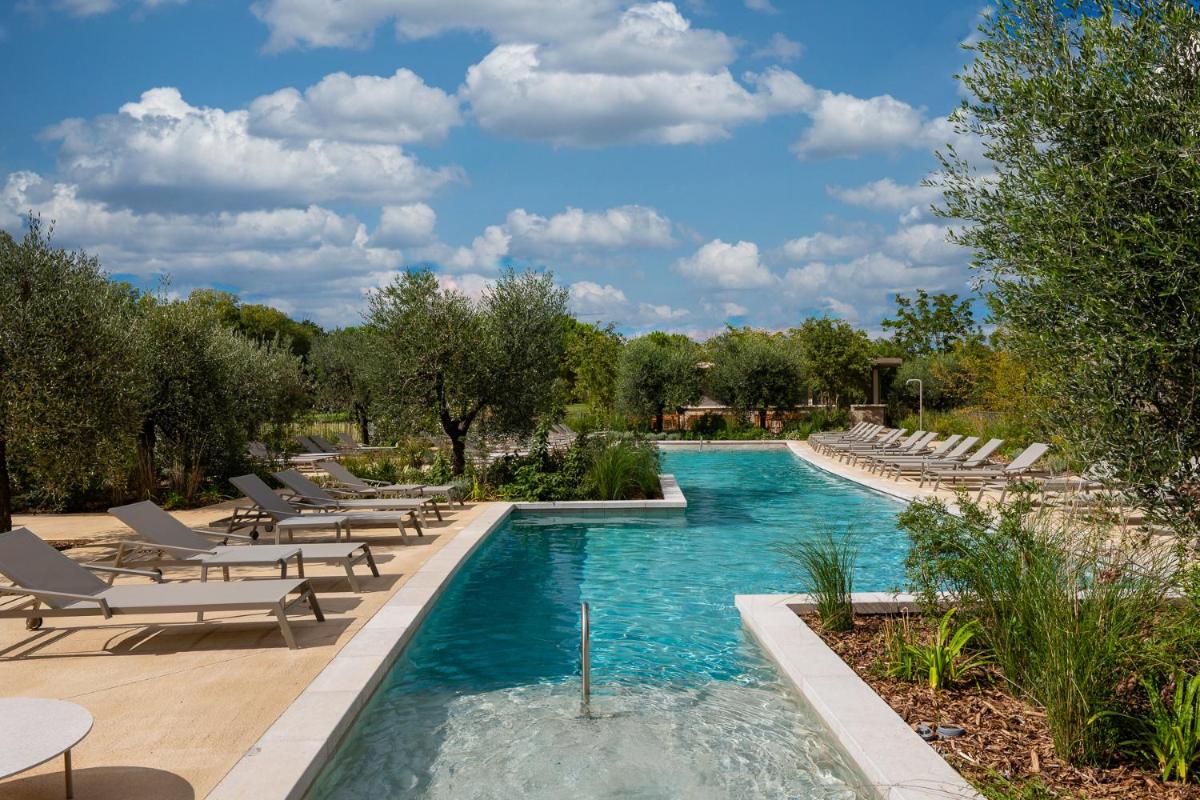 une piscine avec des chaises longues et une piscine dans l'établissement Hôtel Horizon Resort Massane & Spa, à Baillargues