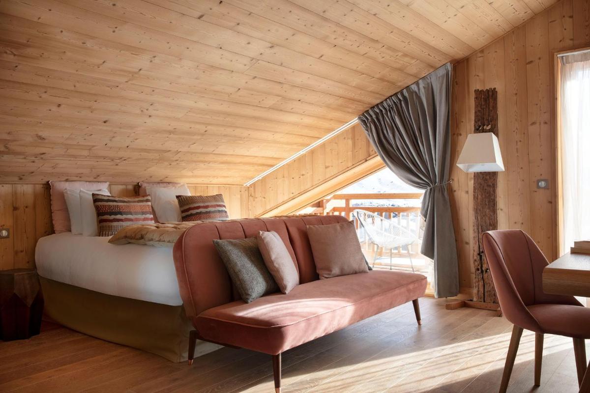 une chambre avec un lit et un canapé dans une pièce dans l'établissement Grandes Rousses Hotel & Spa, à L'Alpe-d'Huez