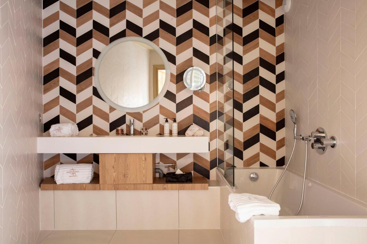 une salle de bain avec un miroir et un lavabo dans l'établissement Grandes Rousses Hotel & Spa, à L'Alpe-d'Huez