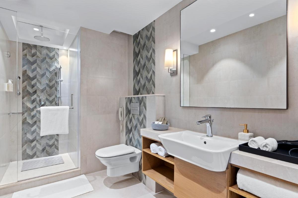 a bathroom with a sink and a toilet and a shower at The Astor - All Suites Hotel Candolim Goa in Candolim a bathroom with a sink and a toilet and a shower at The Astor - All Suites Hotel Candolim Goa in Candolim