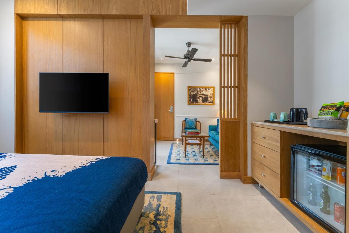 a hotel room with a bed and a flat screen tv at The Astor - All Suites Hotel Candolim Goa in Candolim a hotel room with a bed and a flat screen tv at The Astor - All Suites Hotel Candolim Goa in Candolim