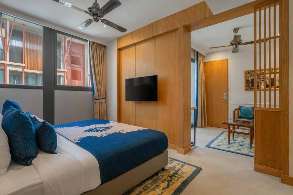 a bedroom with a bed and a flat screen tv at The Astor - All Suites Hotel Candolim Goa in Candolim a bedroom with a bed and a flat screen tv at The Astor - All Suites Hotel Candolim Goa in Candolim