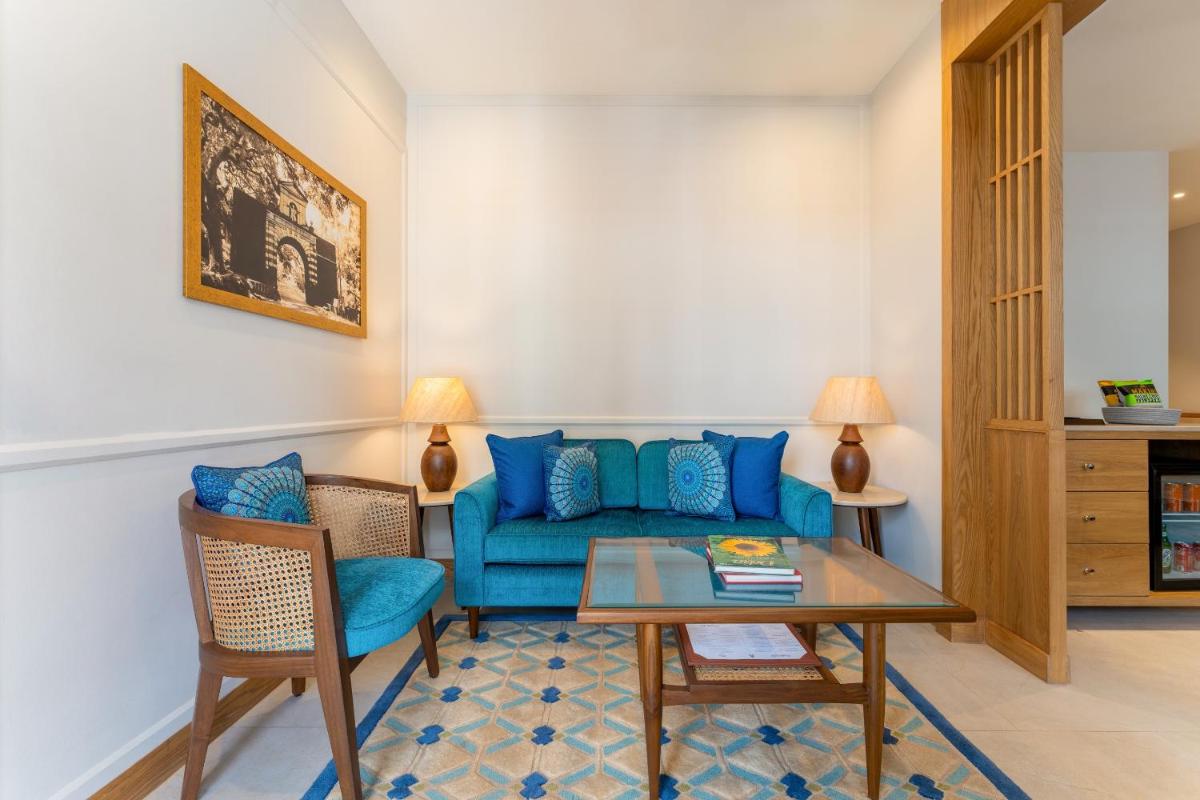 a living room with a blue couch and a table at The Astor - All Suites Hotel Candolim Goa in Candolim a living room with a blue couch and a table at The Astor - All Suites Hotel Candolim Goa in Candolim
