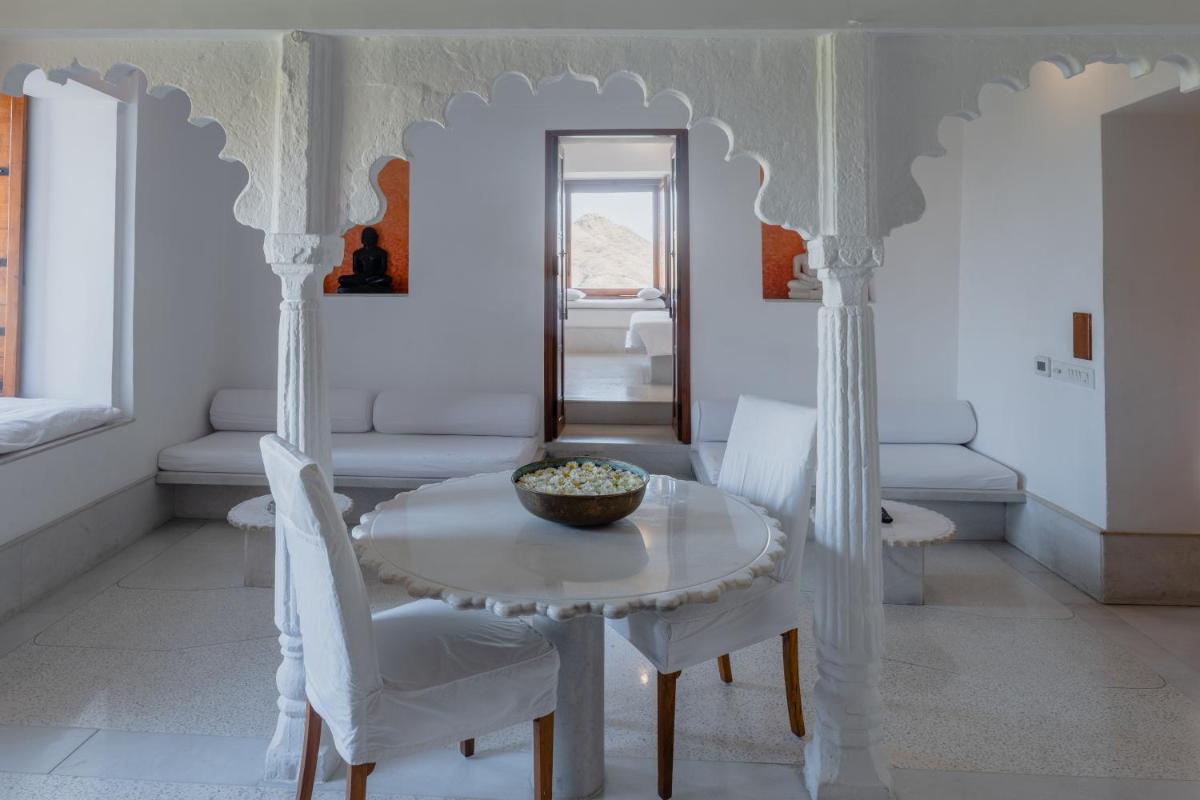 a dining room with a table and white chairs at RAAS Devigarh in Udaipur