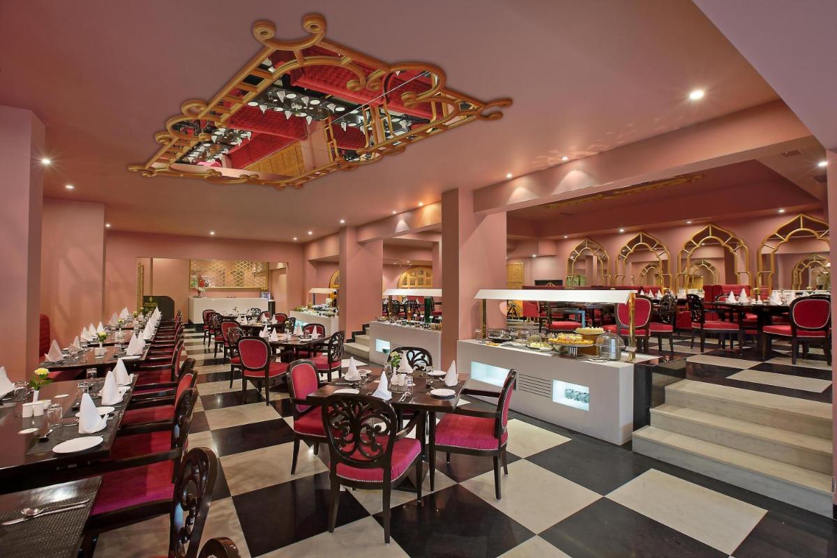a restaurant with tables and chairs and a bar at Hotel Clarks Shiraz in Agra