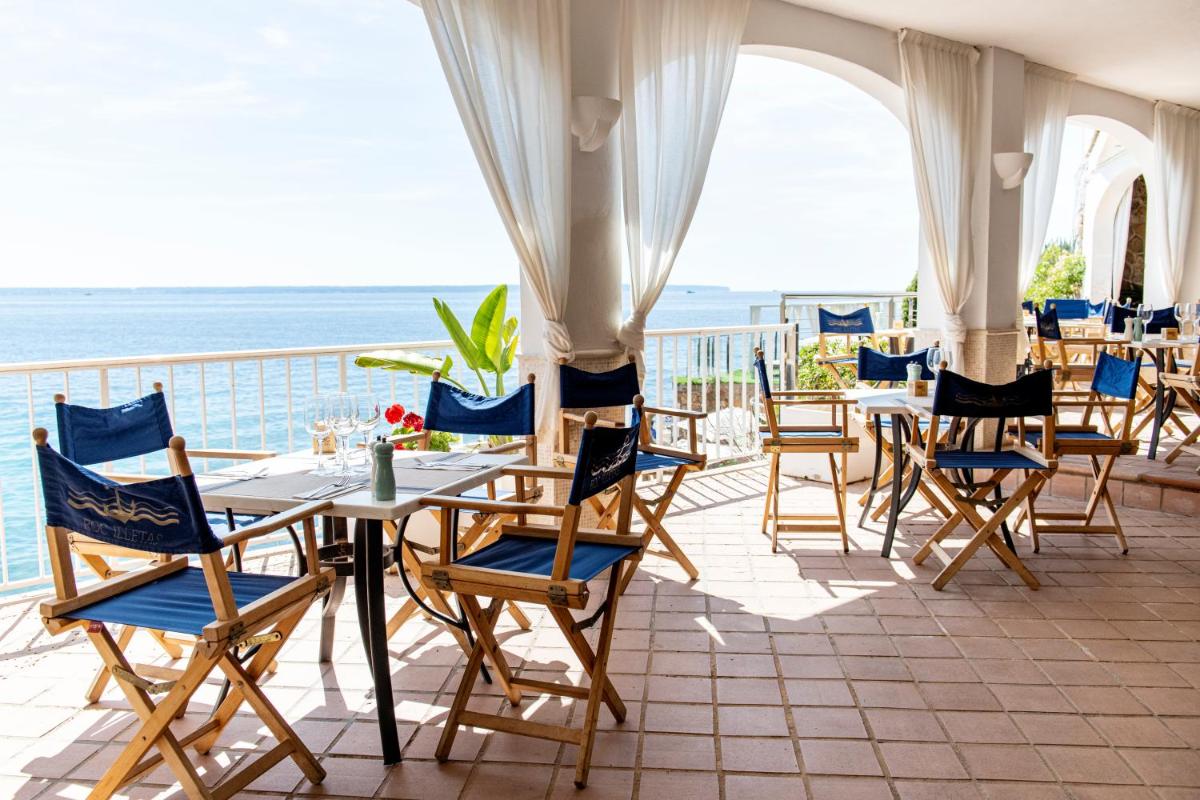 Una mesa y sillas en un balcón con vista al mar. en Hotel ROC Illetas & SPA, en Illetas