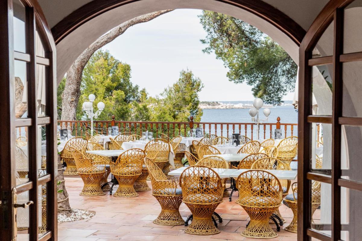 Un patio con mesas y sillas y vista al agua. en Hotel ROC Illetas & SPA, en Illetas 86 fotos más