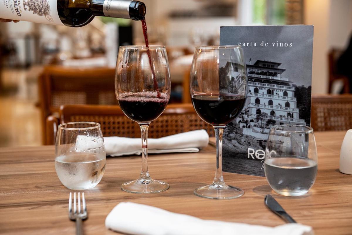 una persona vertiendo vino en dos copas de vino en una mesa en Hotel ROC Illetas & SPA, en Illetas