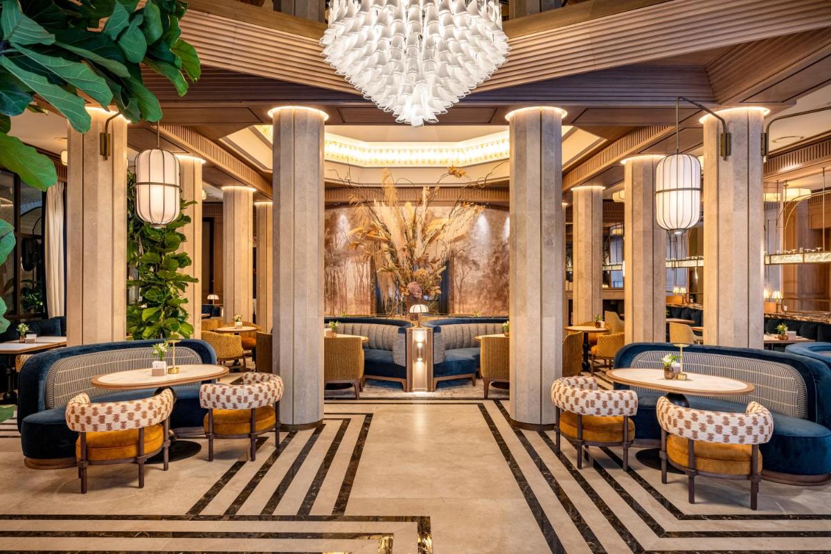 un vestíbulo con mesas y sillas y una lámpara de araña en BLESS Hotel Madrid - The Leading Hotels of the World, en Madrid