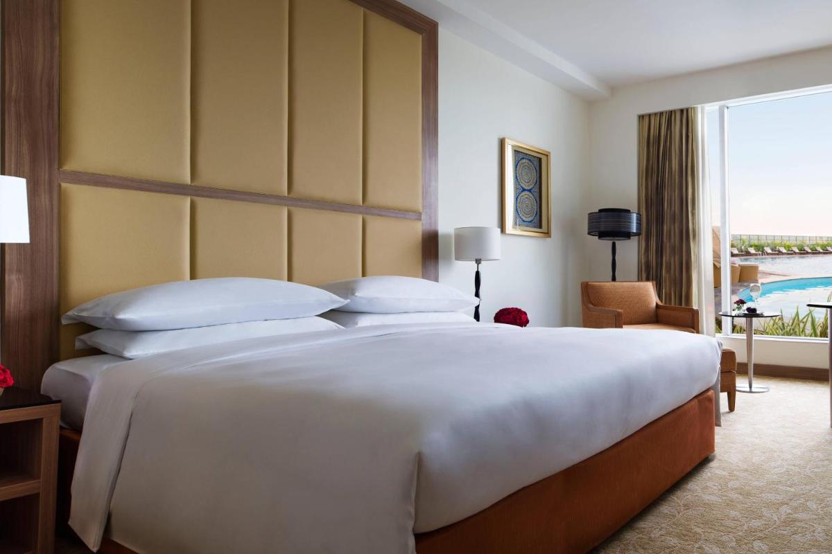 a large white bed in a room with a large window at Bengaluru Marriott Hotel Whitefield in Bengaluru