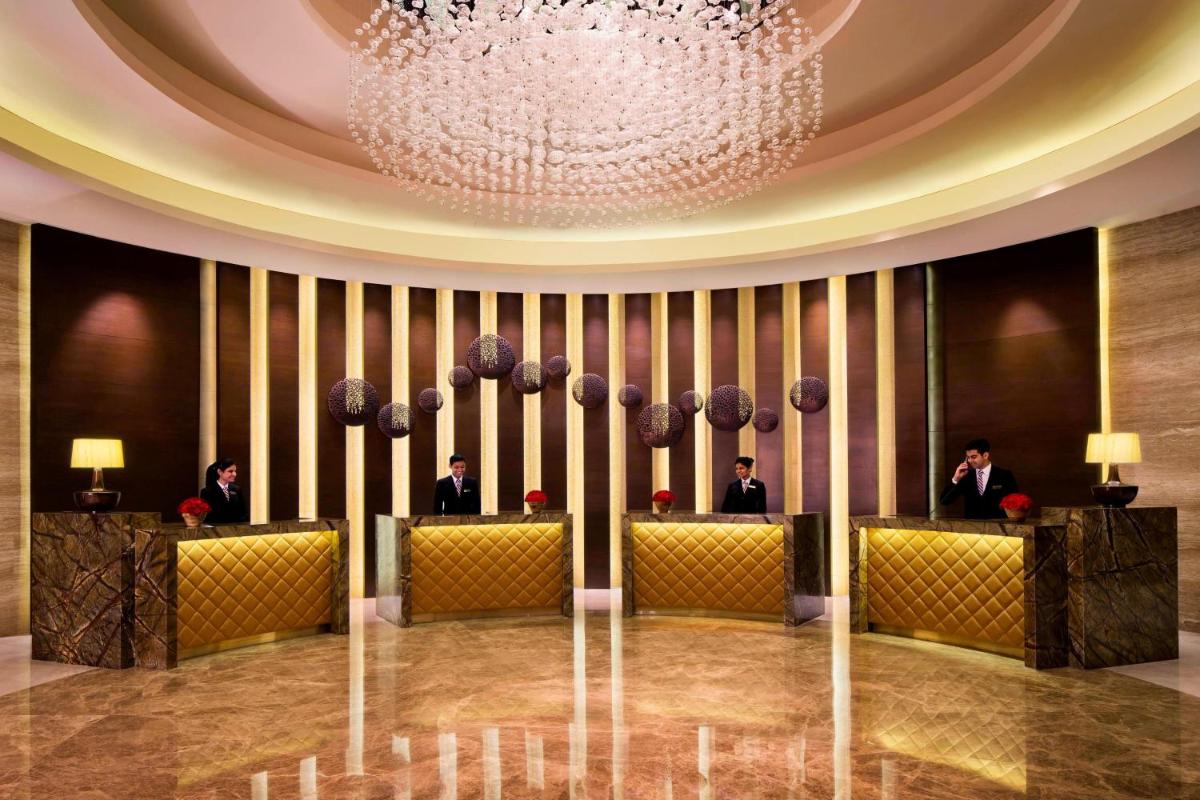 a lobby with a chandelier and people sitting inroups at Bengaluru Marriott Hotel Whitefield in Bengaluru