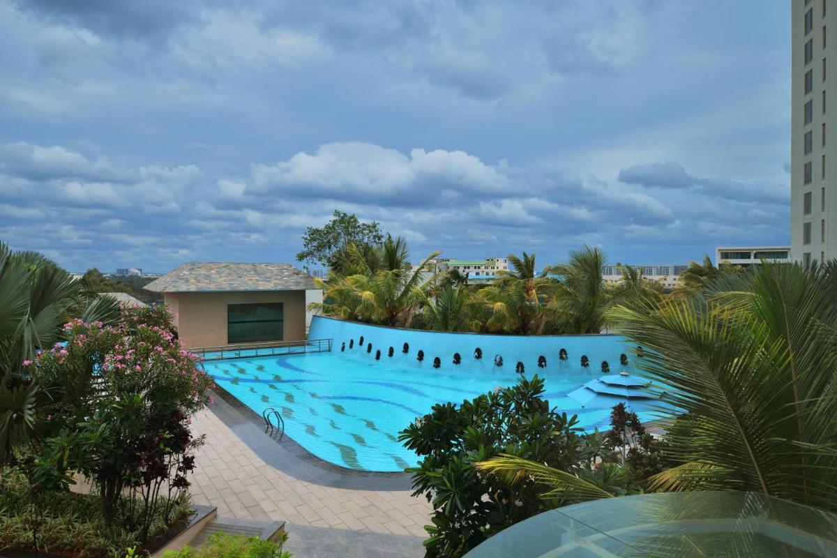 a large swimming pool with people standing around it at Bengaluru Marriott Hotel Whitefield in Bengaluru