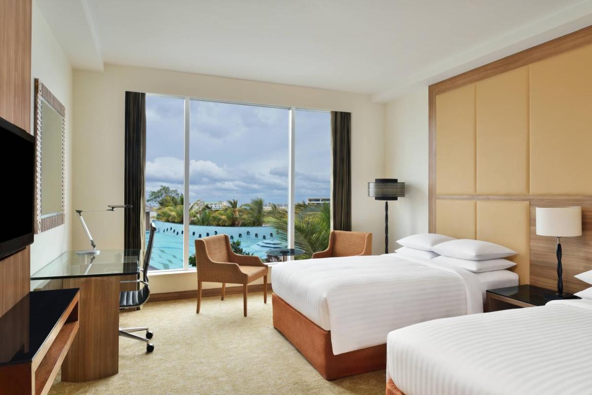 a hotel room with two beds and a view of a pool at Bengaluru Marriott Hotel Whitefield in Bengaluru