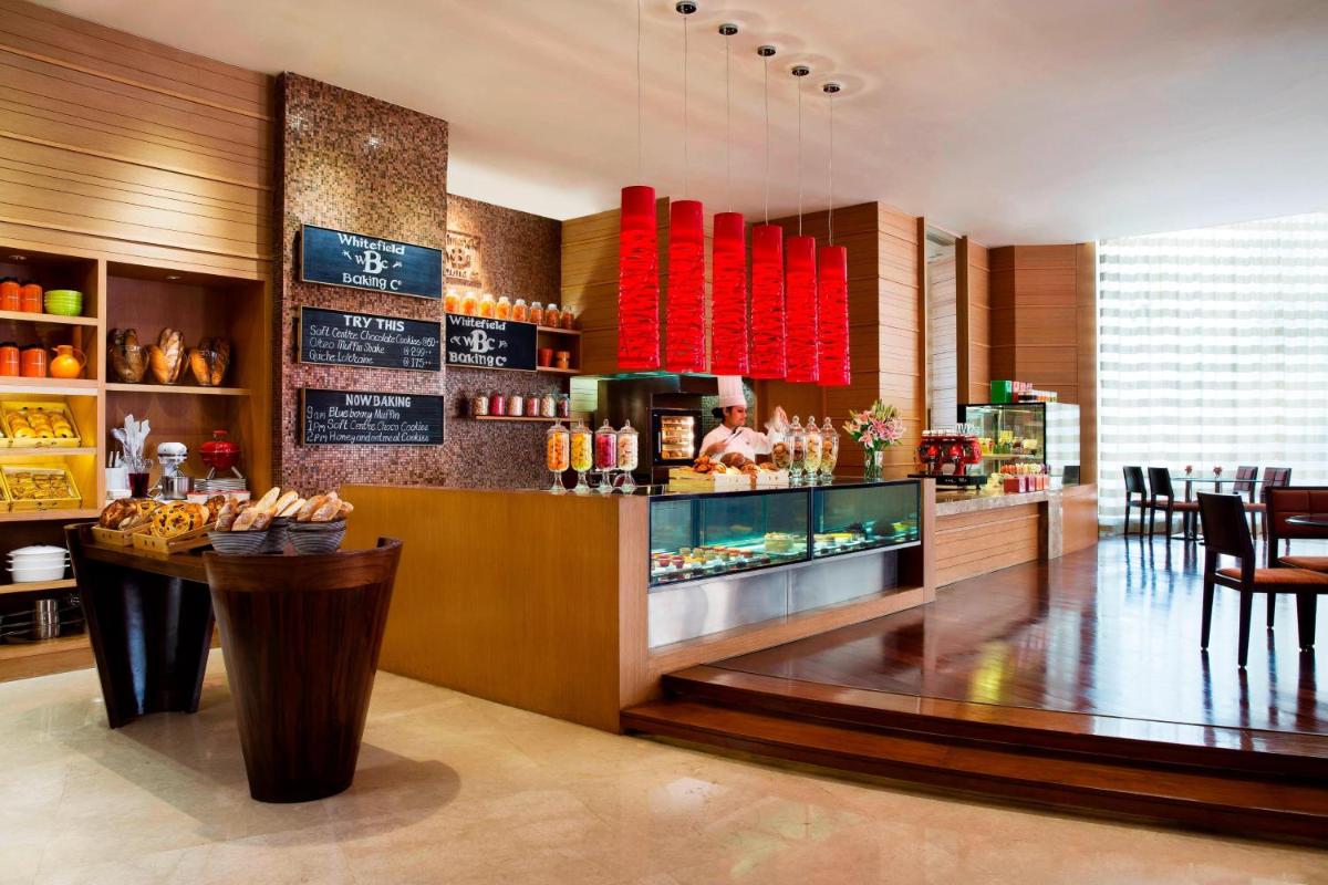 a restaurant with a bar with a chef preparing food at Bengaluru Marriott Hotel Whitefield in Bengaluru