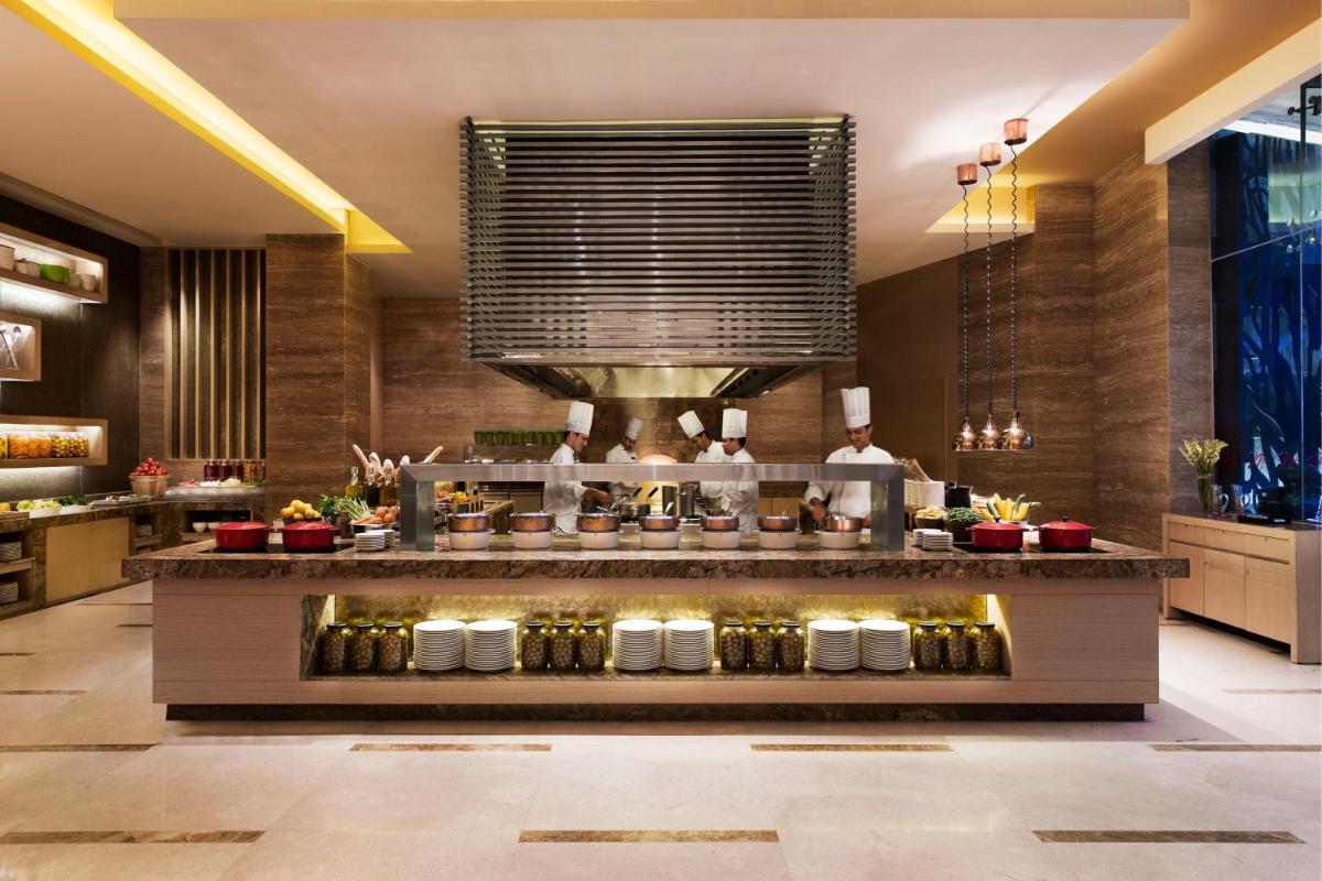 a restaurant with a counter with people preparing food at Bengaluru Marriott Hotel Whitefield in Bengaluru