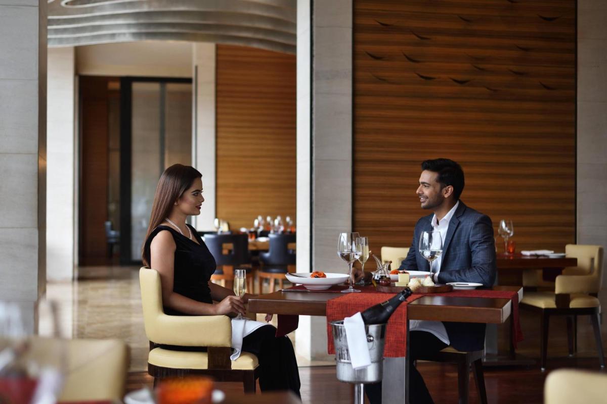 a man and woman sitting at a table in a restaurant at Bengaluru Marriott Hotel Whitefield in Bengaluru