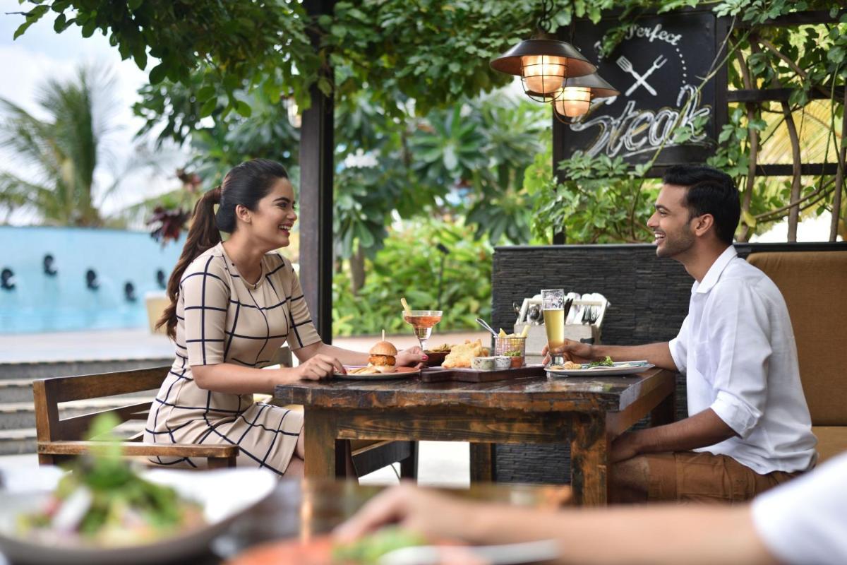 a man and woman sitting at a table in a restaurant at Bengaluru Marriott Hotel Whitefield in Bengaluru