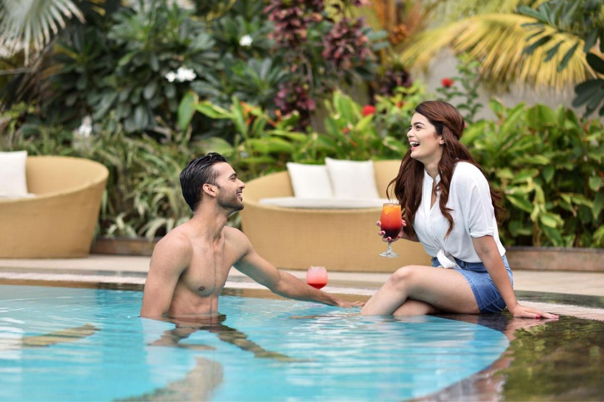 a man and a woman sitting in a swimming pool at Bengaluru Marriott Hotel Whitefield in Bengaluru