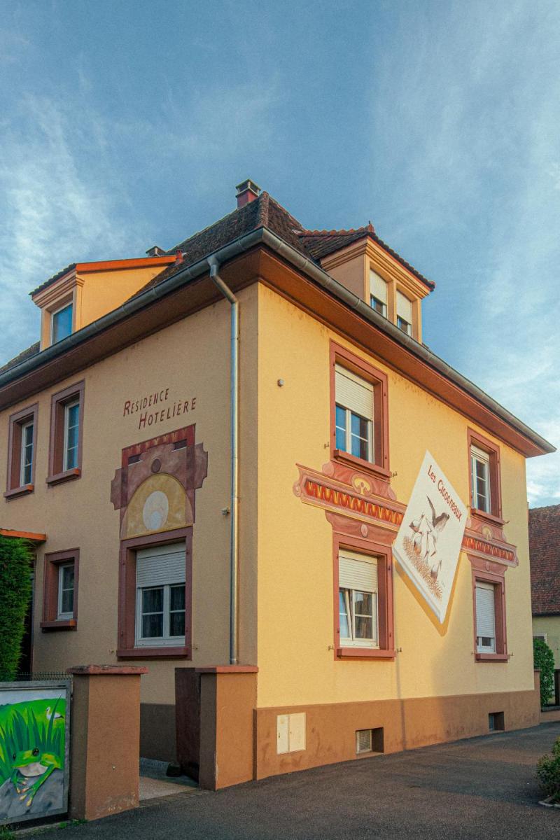 un bâtiment jaune avec un panneau sur son côté dans l'établissement Résidence Les Cigogneaux, à Ostheim un bâtiment jaune avec un panneau sur son côté dans l'établissement Résidence Les Cigogneaux, à Ostheim