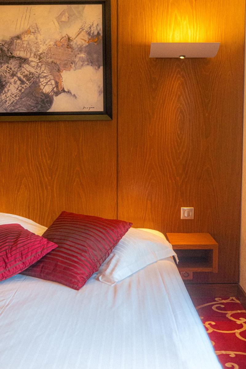 une chambre avec un lit avec des oreillers rouges et blancs dans l'établissement Résidence Les Cigogneaux, à Ostheim une chambre avec un lit avec des oreillers rouges et blancs dans l'établissement Résidence Les Cigogneaux, à Ostheim
