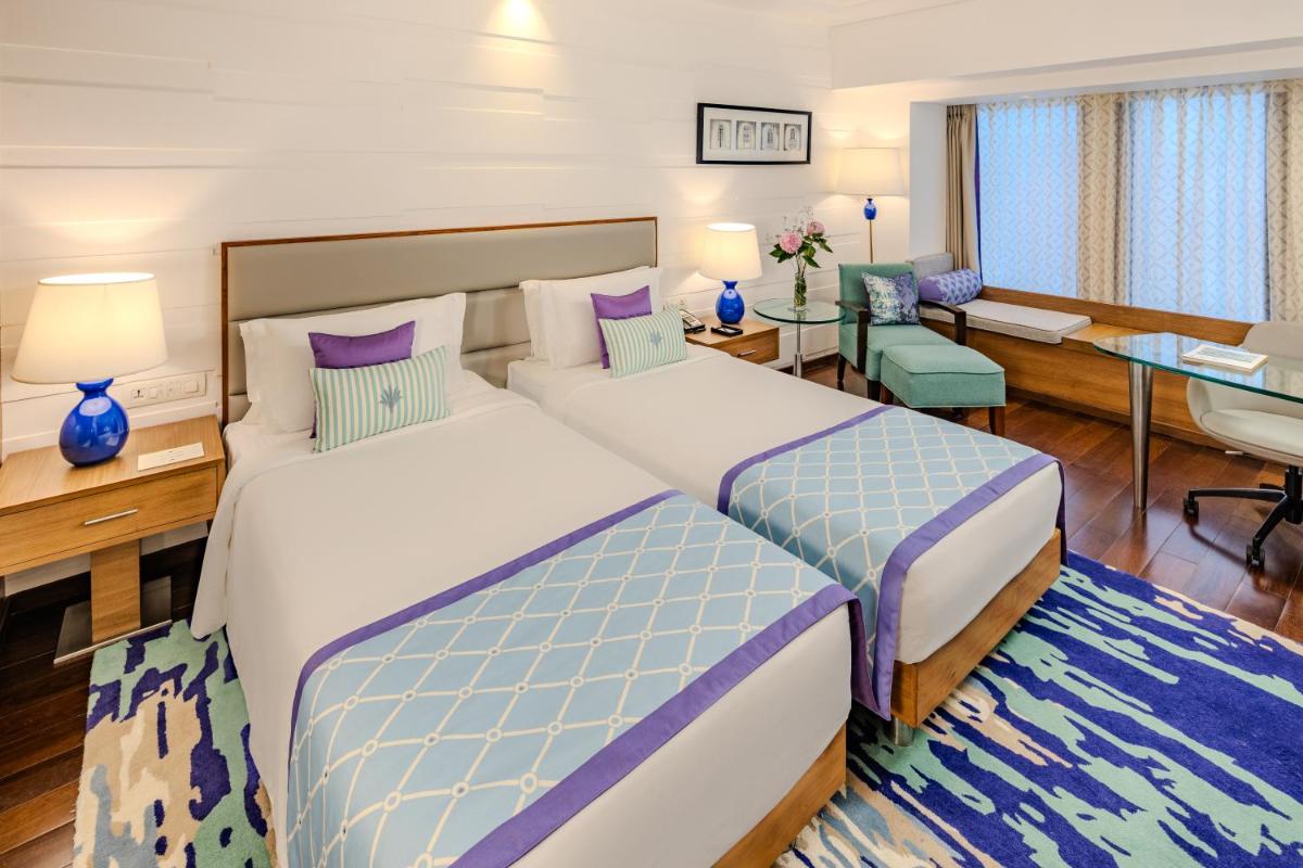 a hotel room with two beds and a desk at Vivanta Goa, Panaji in Panaji a hotel room with two beds and a desk at Vivanta Goa, Panaji in Panaji