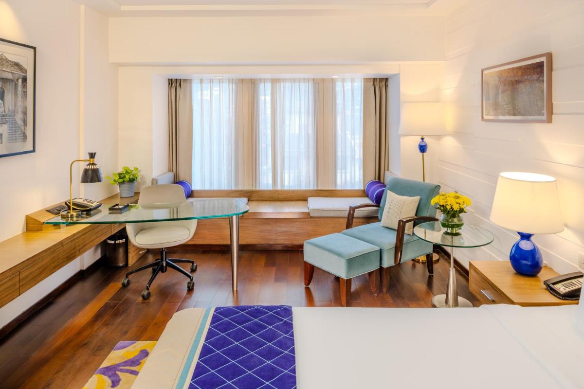 a hotel room with a bed and a desk and chairs at Vivanta Goa, Panaji in Panaji a hotel room with a bed and a desk and chairs at Vivanta Goa, Panaji in Panaji