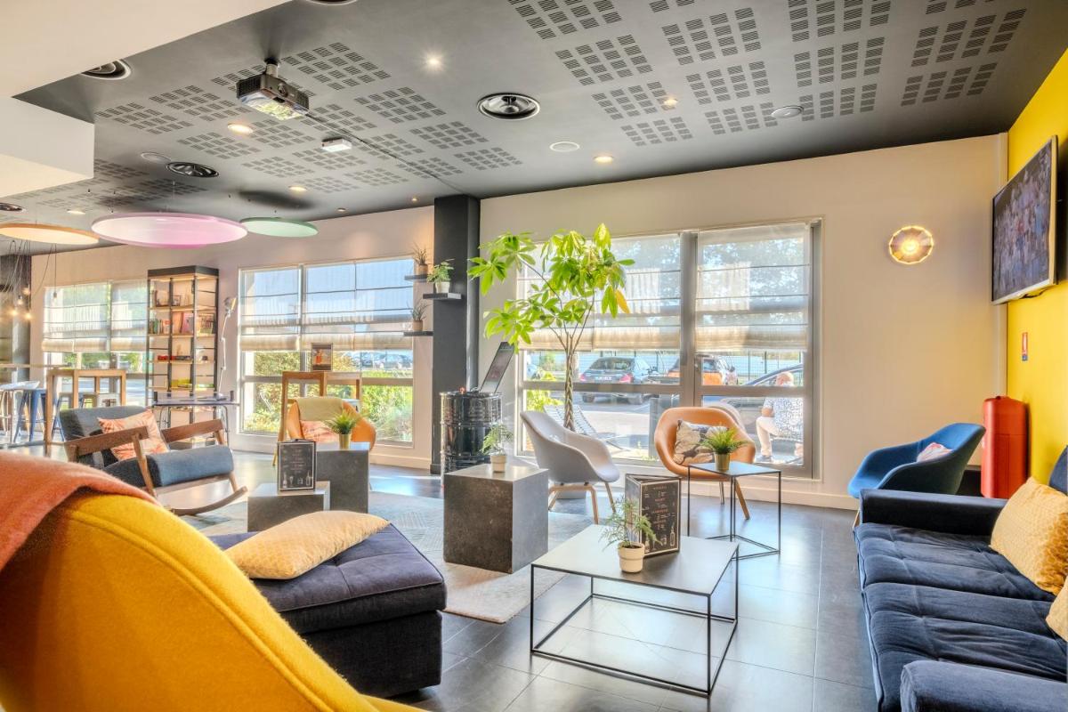 une salle d'attente avec des canapés et des chaises dans l'établissement Campanile Roissy - Aéroport CDG - Le Mesnil Amelot, au Mesnil-Amelot