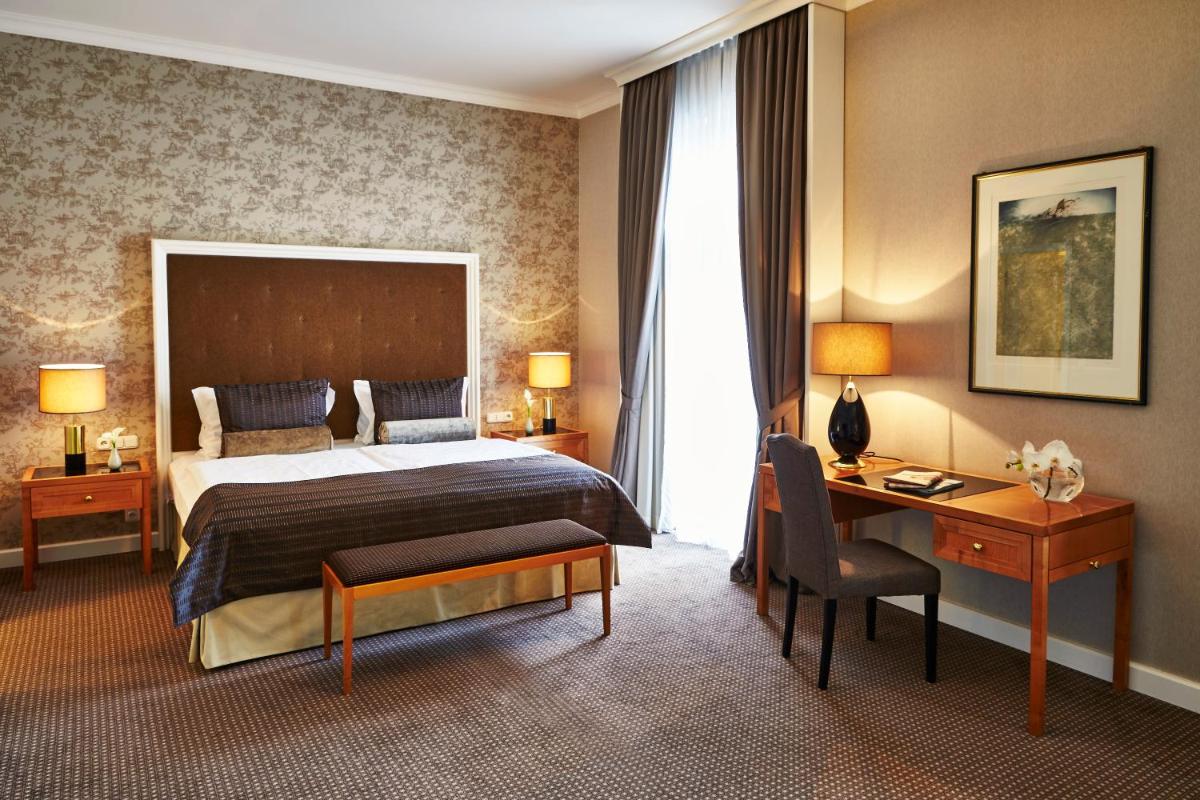 ein Hotelzimmer mit einem Bett und einem Schreibtisch und einem Schreibtisch in der Unterkunft Steigenberger Icon Frankfurter Hof in Frankfurt am Main ein Hotelzimmer mit einem Bett und einem Schreibtisch und einem Schreibtisch in der Unterkunft Steigenberger Icon Frankfurter Hof in Frankfurt am Main