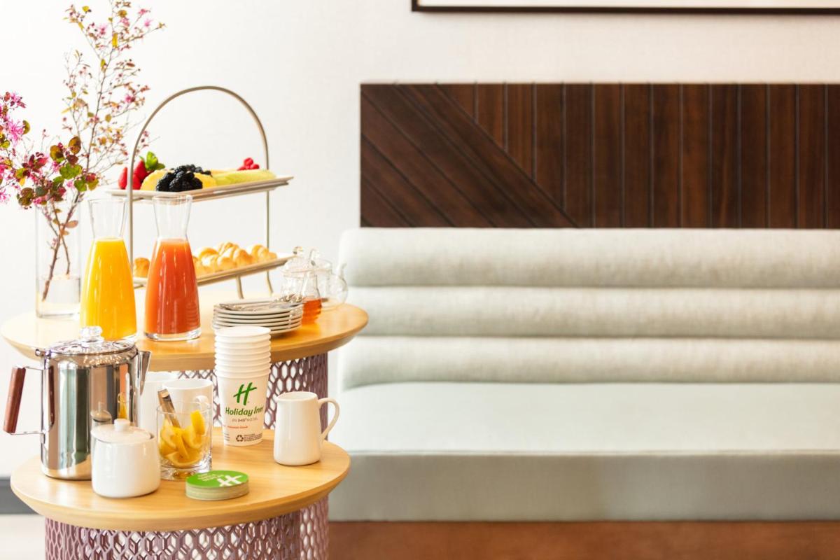 a table with cups and plates of food on it at Holiday Inn New Delhi Aerocity by IHG in New Delhi