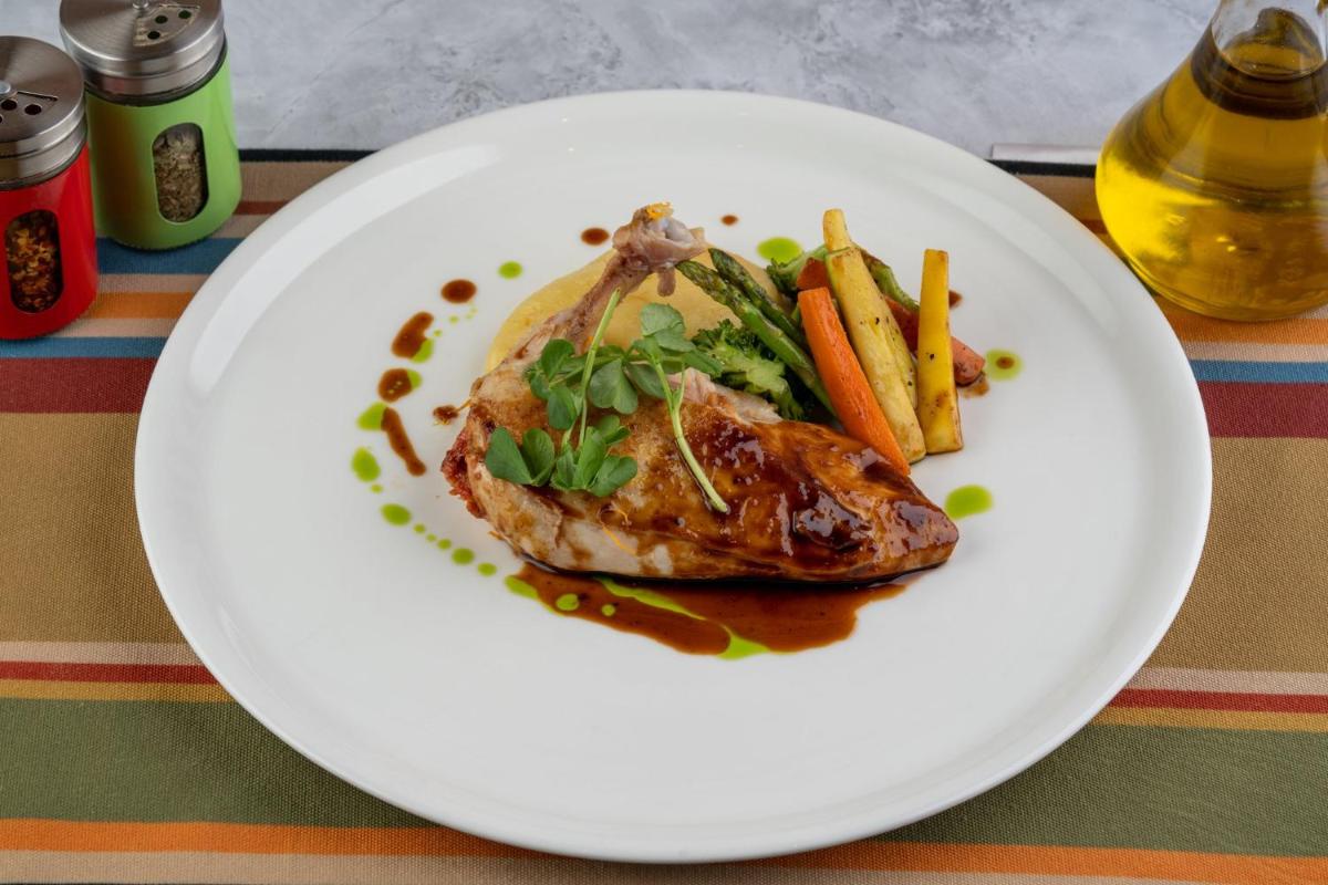 a white plate with a piece of meat and french fries at Holiday Inn New Delhi Aerocity by IHG in New Delhi