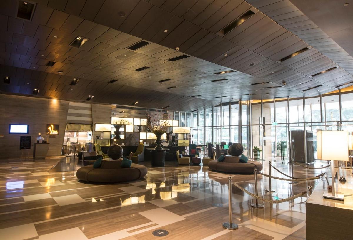 a lobby with two people sitting on couches in a building at Holiday Inn New Delhi Aerocity by IHG in New Delhi