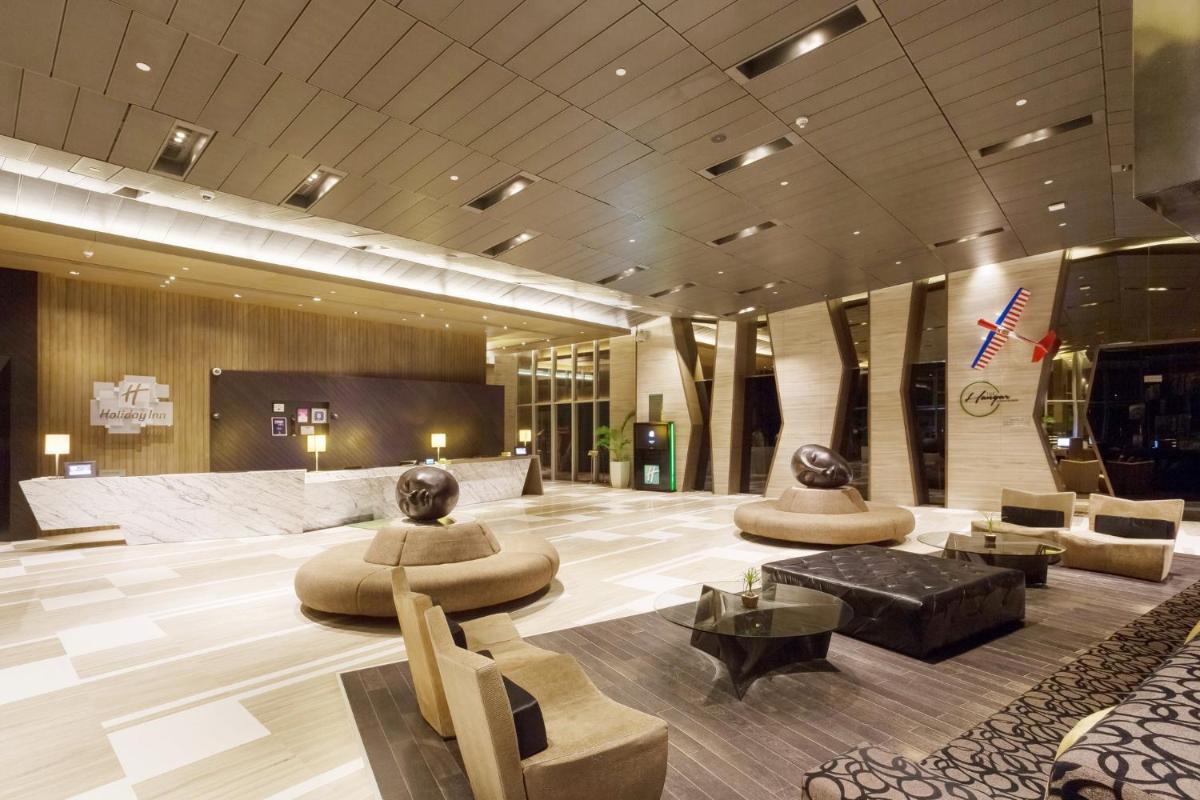 a lobby with couches and tables in a building at Holiday Inn New Delhi Aerocity by IHG in New Delhi